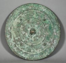 A Chinese Patinated Bronze Circular Mirror of Archaic Form, the plain silvered face with green