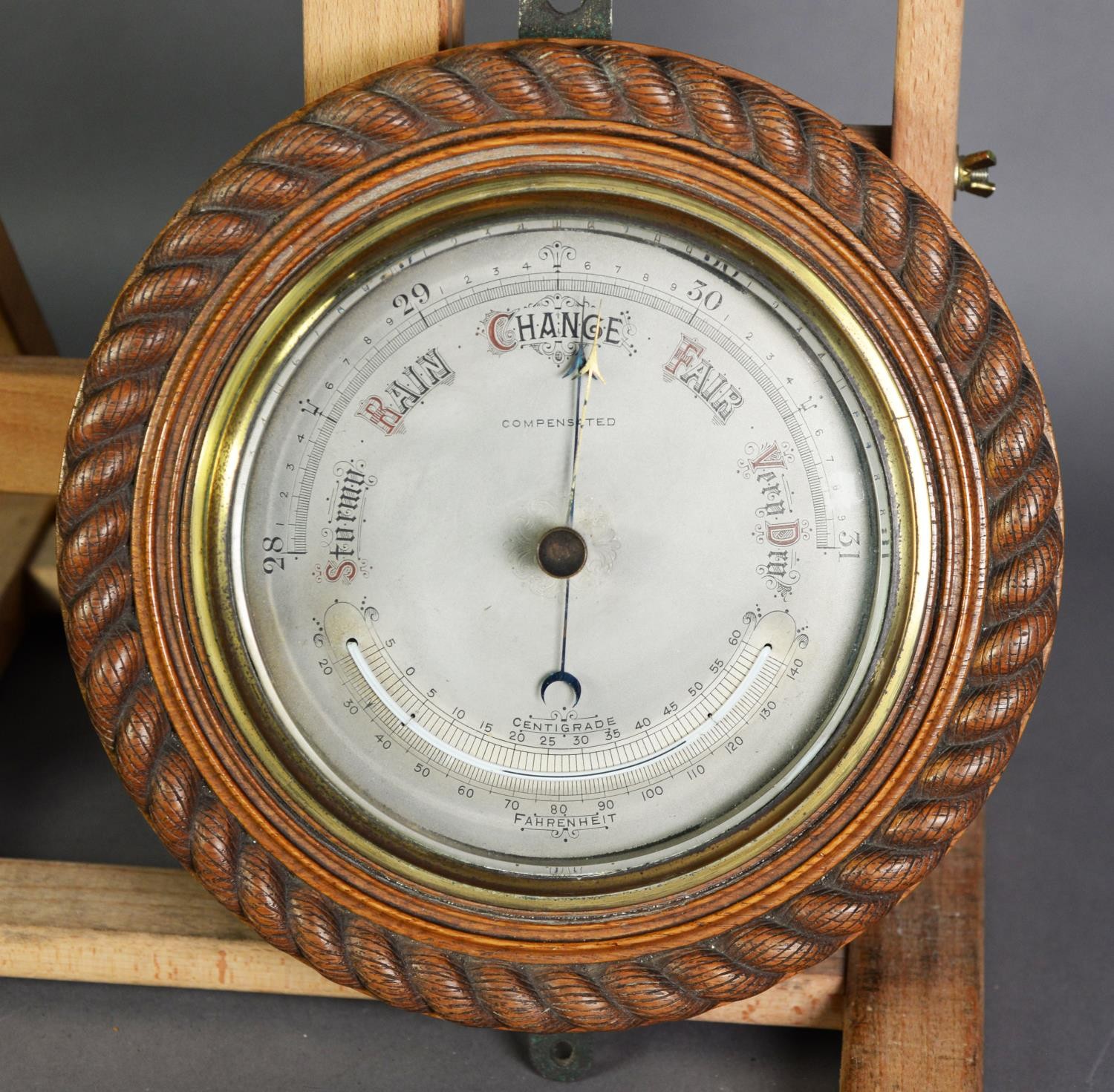 OAK FRAMED COMBINATION ANEROID BAROMETER AND THERMOMETER, the silvered dial reading from 28-31,