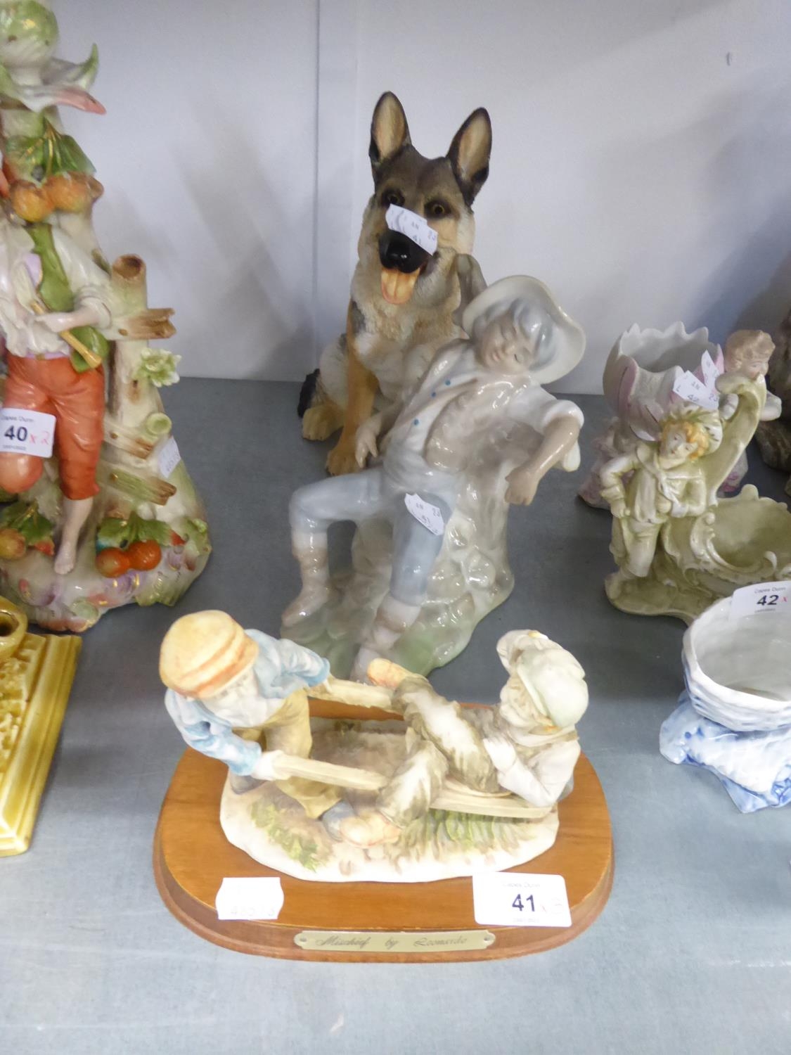 A RESIN MODEL OF AN ALSATIAN DOG, SEATED; A CHINA FIGURE OF A BOY ASLEEP AND A RESIN SEE-SAW