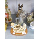 A RESIN MODEL OF AN ALSATIAN DOG, SEATED; A CHINA FIGURE OF A BOY ASLEEP AND A RESIN SEE-SAW