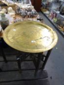 EASTERN BRASS TRAY TOP FOLDING TABLE WITH INCISED SCRIPT AND ARABESQUES, 23in (58.5cm) diameter