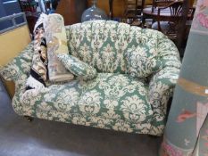 A TWO SEATER BUTTON BACK SETTEE, HAVING SCROLL ARMS, COVER IN CREAM AND GREEN FABRIC, RAISED ON