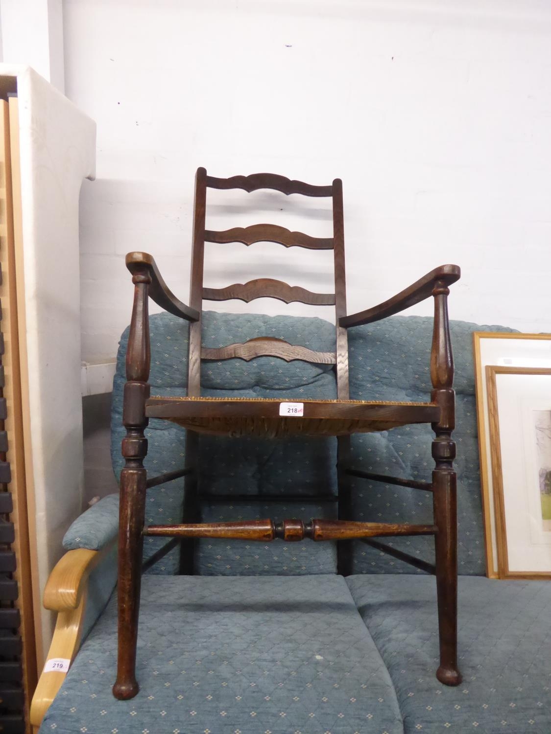 AN ANTIQUE OAK LADDER BACK OPEN ARMCHAIR WITH RUSH SEAT