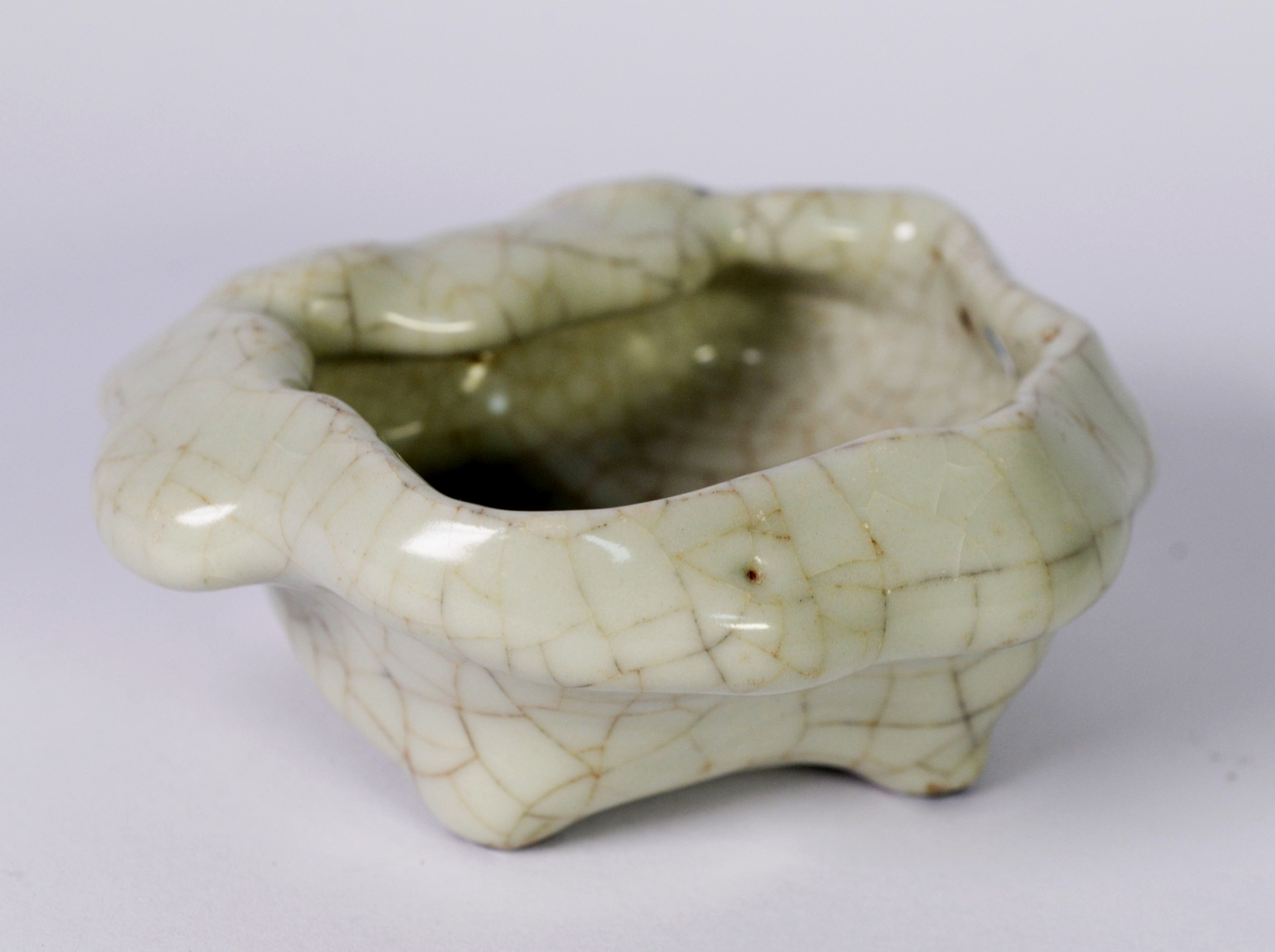 CHINESE PALE CELADON CRACKLE GLAZED PORCELAIN BOWL OF IRREGULAR FORM, raised on four stud feet,