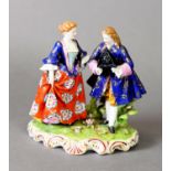 19TH CENTURY FIGURE GROUP OF A LADY AND GENTLEMAN IN 18TH CENTURY DRESS, he with tricorn hat, red