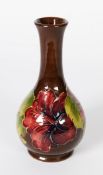 WALTER MOORCROFT ‘HIBISCUS’ PATTERN TUBE LINED POTTERY BOTTLE VASE, of footed form, decorated in