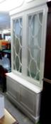 A LARGE, WHITE FINISH DISPLAY CABINET ENCLOSED BY TWO ASTRAGAL GLAZED DOORS, ON AN ADVANCED CUPBOARD