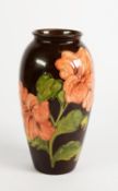 WALTER MOORCROFT LIMITED EDITION HIBISCUS PATTERN TUBE LINED POTTERY VASE WITH A BROWN GROUND, of