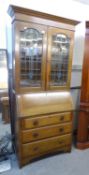 AN EARLY TWENTIETH CENTURY OAK BUREAU BOOKCASE, THE UPPER SECTION HAVING COLOURED LEAD GLAZED DOORS