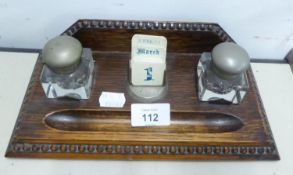 AN OAK OBLONG PEN AND INKSTAND WITH RAISED BACK, TWO GLASS SQUARE INKWELLS AND CENTRE PERPETUAL