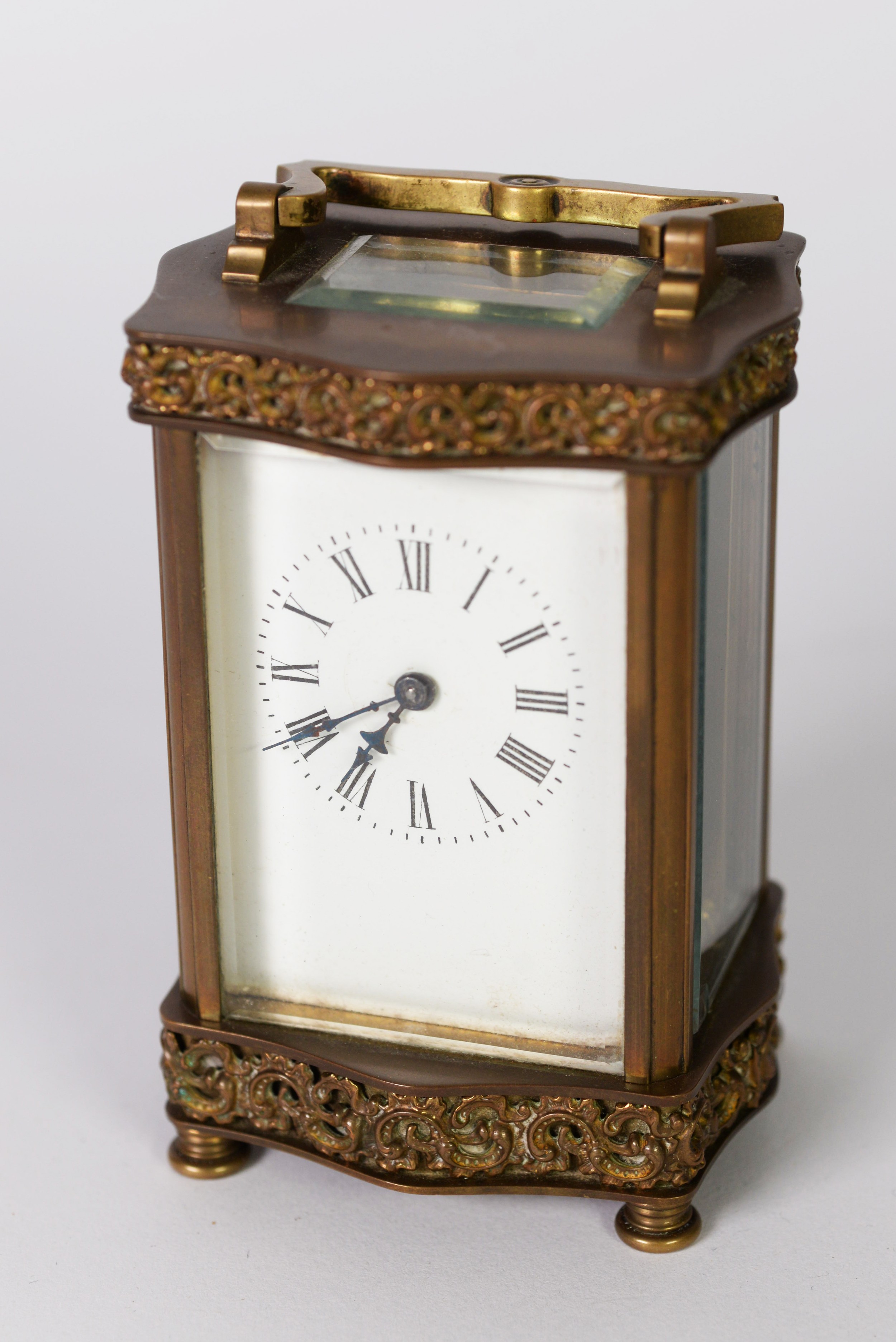 EARLY 20th CENTURY GILT BRASS DECORATIVE CARRIAGE CLOCK, the serpentine sided top and bottom applied