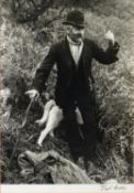 TWO VINTAGE BLACK AND WHITE PHOTOGRAPHIC PRINTS, ONE of a man with dogs amongst ferns, signed BEN