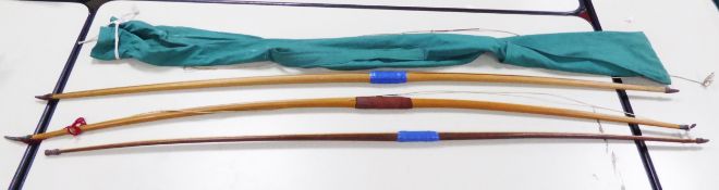 THREE LAMINATED WOOD LONG BOWS, each with carved horn neck or end pieces, 73in (185.4cm) long and