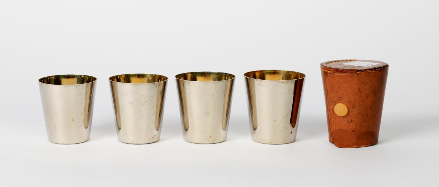 SET OF FOUR GERMAN SILVER PLATED NESTING SMALL TAPERING BEAKERS with gilt interiors, in tan