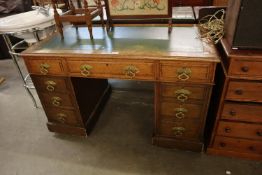 AN OAK DOUBLE PEDESTAL DESK WITH GREEN LEATHER INSET TOP, HAVING TWO BANKS OF FOUR DRAWERS AND A