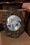 A SMALL CIRCULAR WALL MIRROR, IN EMBOSSED STAMPED BRASS BROAD FRAME WITH PUTTO AND FLOWERS