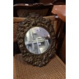 A SMALL CIRCULAR WALL MIRROR, IN EMBOSSED STAMPED BRASS BROAD FRAME WITH PUTTO AND FLOWERS
