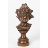 SMALL EARLY 20th CENTURYCAST BRONZE BUST OF A GIRL with curly hair partly in a bun, raised on a