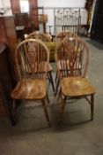 A SET OF FOUR HARDWOOD WHEEL BACKED SINGLE CHAIRS, WITH PANEL SEATS