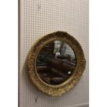 A CIRCULAR WALL MIRROR, IN EMBOSSED GILT FRAME