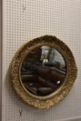 A CIRCULAR WALL MIRROR, IN EMBOSSED GILT FRAME