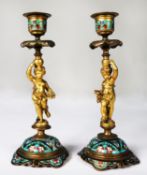 PAIR OF TWENTIETH CENTURY ORMOLU AND CHAMPLEVÉ FIGURAL CANDLESTICKS, each modelled as a cherub,