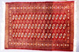 FINELY KNOTTED PAKISTAN BOKHARA RUG, with the three rows each of 16 guls, crimson and orange on