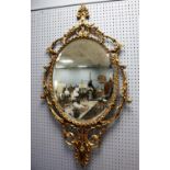 MODERN GILT METAL FRAMED WALL MIRROR, the oval, bevel edged plate within a scroll pierced frame,