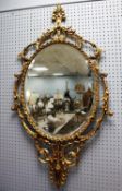 MODERN GILT METAL FRAMED WALL MIRROR, the oval, bevel edged plate within a scroll pierced frame,