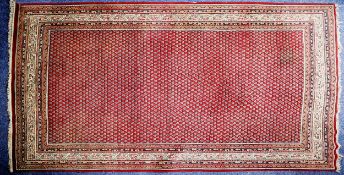 EASTERN CARPET WITH ALL-OVER SMALL BOTEH PATTERN, on a crimson field, off-white and floral meander