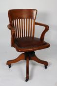 EARLY/ MID TWENTIETH CENTURY OAK RECLINING AND REVOLVING DESK CHAIR, the shaped top rail above a
