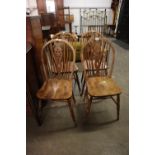 A SET OF FOUR HARDWOOD WHEEL BACKED SINGLE CHAIRS, WITH PANEL SEATS