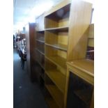 A TEAK EFFECT STORE CUPBOARD AND TWO WOOD EFFECT OPEN BOOKCASES, ONE WITH A TOP CUPBOARD (3)