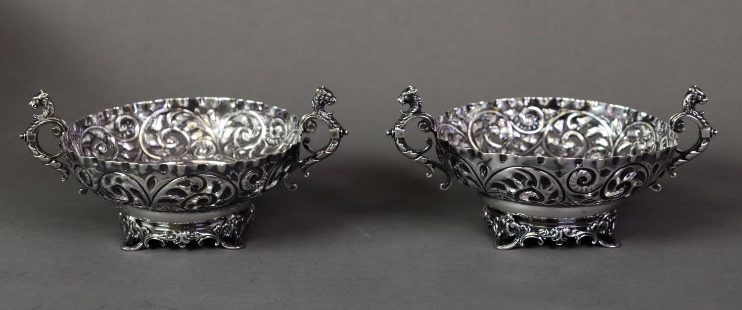 LATE VICTORIAN PAIR OF EMBOSSED AND PIERCED SILVER TWO HANDLED BON BON DISHES, each with dragon’s