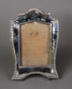 GEORGE V EMBOSSED SILVER FRONTED DESK TOP PHOTOGRAPH FRAME, with arched top and slender stylised