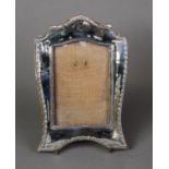 GEORGE V EMBOSSED SILVER FRONTED DESK TOP PHOTOGRAPH FRAME, with arched top and slender stylised