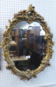 AN OVAL WALL MIRROR, IN ORNATE GILT FRAME