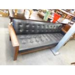 A TEAK FRAMED SETTEE, COVERED IN BLACK BUTTON UPHOLSTERED LEATHER, 7'6" LONG, BY WESTNOFA FURNITURE,