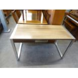 A STYLISH TEAK WRITING TABLE, WITH BRUSHED STEEL CONTINUOUS END SUPPORTS, ONE SMALL DRAWER, LIFT-