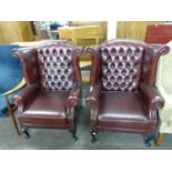 A PAIR OF GEORGIAN STYLE WINGED EASY CHAIRS, IN DARK TAN HIDE, EACH WITH BUTTON UPHOLSTERED BACK,