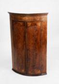 GEORGE III INLAID FLAME CUT MAHOGANY, BOW FRONTED CORNER CUPBOARD, the moulded cornice above a