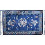 ORIENTAL RUG, the royal blue field decorated with centre mon and cloud scrolls, utensils and urns of