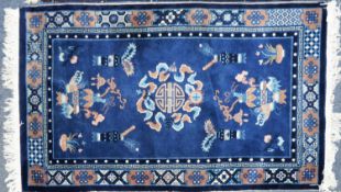 ORIENTAL RUG, the royal blue field decorated with centre mon and cloud scrolls, utensils and urns of