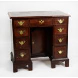 GEORGE III MAHOGANY AND LATER KNEEHOLE DESK, the crossbanded and moulded oblong top above nine