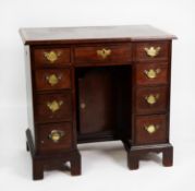 GEORGE III MAHOGANY AND LATER KNEEHOLE DESK, the crossbanded and moulded oblong top above nine