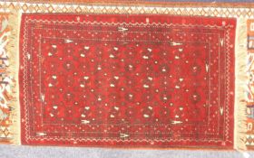 TURKOMAN BOKHARA RUG, crimson with stencilled black pattern with white highlights, multiple border