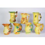 SIX BURLEIGH WARE YELLOW GLAZED POTTERY JUGS WITH MOULDED HANDLES, including: PIED PIPER, PARROT,