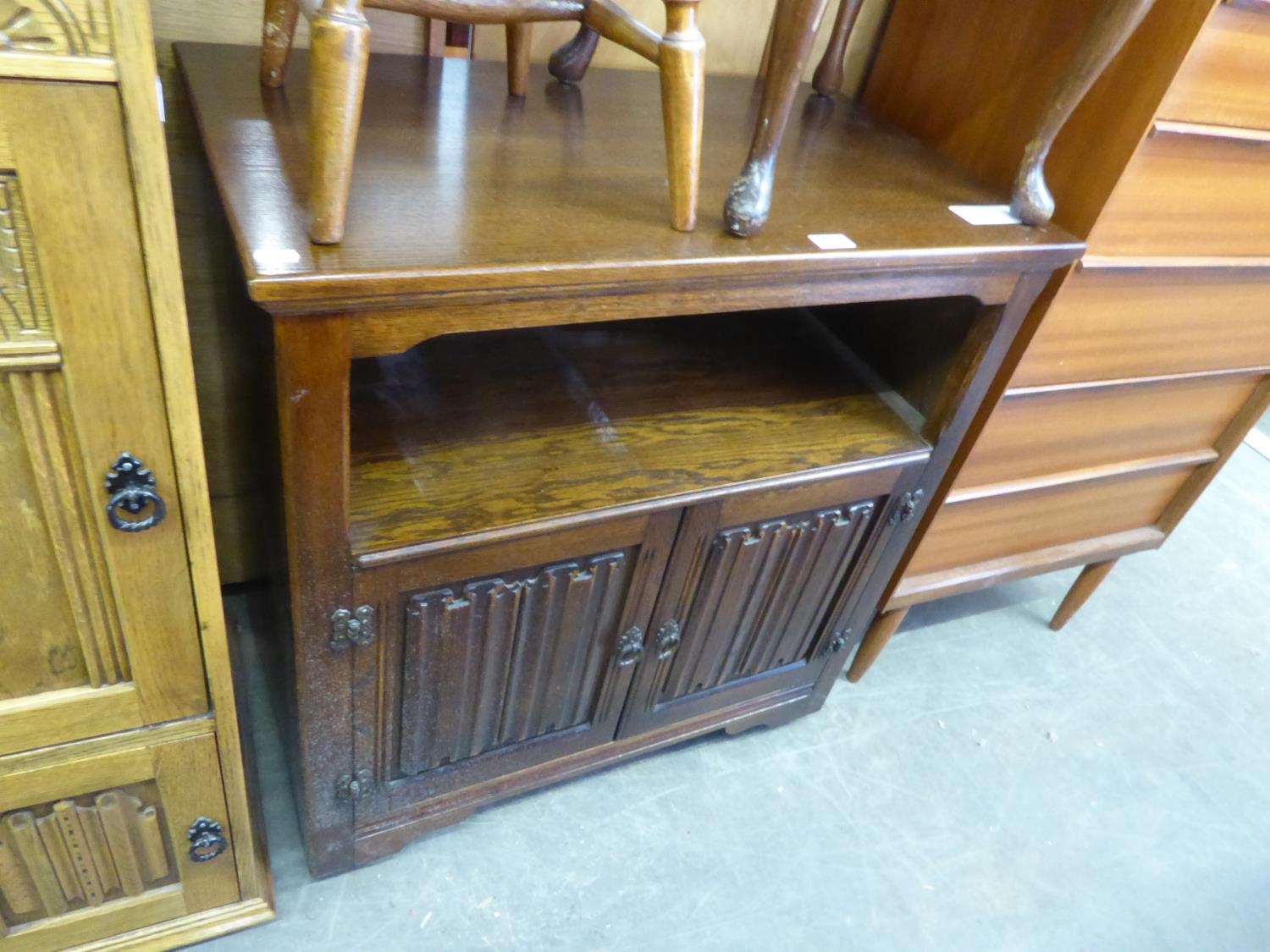 A WOOD BROS. OAK TV CABINET, HAVING AN OPEN SECTION OVER TWO LINEN FOLD PANEL DOORS