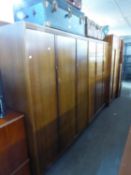 A PAIR OF TEAK THREE DOOR SEMI-FITTED WARDROBES AND A MATCHING CHEST OF FIVE LONG DRAWERS, BY