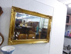 A LARGE OBLONG BEVELLED EDGE WALL MIRROR IN SWEPT GILT WOOD FRAME, 25” X 36” OVER ALL